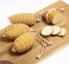 Smoked cheese products wrapped in netting, arranged on a wooden board with some slices cut. Produktbild-Vorschau