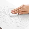 A hand is wiping a surface with a white cloth, with water droplets on the surface. Produktbild-Vorschau