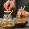 A collage showing a hand placing the lid on a glass honey jar and another shot of the honey jar being held. Produktbild-Vorschau