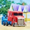 A toy truck, likely Optimus Prime from Transformers, is shown in a backyard setting with a house in the background. Podgląd zdjęcia produktu
