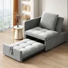 A gray sofa bed is shown in a living room setting with a small side table and a window in the background. Produktbild-Vorschau