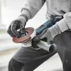 A person wearing gloves is holding an angle grinder and attaching a grinding disc. Produktbild-Vorschau