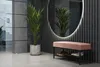 A modern entryway with a pink upholstered bench and shoe rack, a large oval mirror with LED lighting, and a potted plant. Produktbild-Vorschau