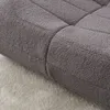 A close-up view of a textured gray sofa or cushion placed on a lighter gray carpet. Náhled obrázku produktu