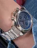 A close-up shot of a woman's wrist wearing a silver and blue Guess watch. Voir les images du produit