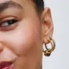 Close-up of a person's ear wearing gold hoop earrings with a charm. Produktbild-Vorschau
