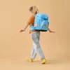 A young girl wearing a backpack walks with her arms outstretched. Produktbild-Vorschau