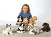 A young girl is surrounded by several plush dog toys. Produktbild-Vorschau
