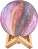 A galaxy-patterned moon lamp on a wooden stand. Anteprima dell’immagine prodotto