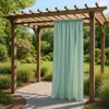 A light green curtain hangs from a wooden pergola in a garden setting. Podgląd zdjęcia produktu
