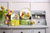 A collection of Easter-themed Villeroy & Boch porcelain items displayed on a grey desk with tulips. Produktbild-Vorschau