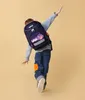 A child wearing a backpack is posing dynamically against a plain background. Anteprima dell’immagine prodotto