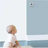 A baby looking up at a small digital device mounted on a wall. Podgląd zdjęcia produktu