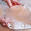 Hands holding a white duvet with visible snap buttons. Produktbild-Vorschau