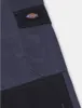 A close-up view of a pair of navy blue work pants with a black cargo pocket and a Dickies logo patch. Podgląd zdjęcia produktu