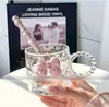A close-up shot of a clear glass mug with a pink bow and a pink beaded spoon, with a vinyl record in the background. Anteprima dell’immagine prodotto