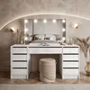 A modern bedroom vanity with a mirror and lights, set against a textured wall and a bed in the background. Náhled obrázku produktu