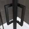 Close-up of black shower door handles against a tiled wall and white shower base. Produktbild-Vorschau