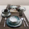 A table setting with dinnerware, glasses, and decorative pinecones. Voir les images du produit
