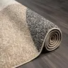 A close-up view of a rolled-up rug with a geometric pattern, showing its textured surface and rolled edge. Produktbild-Vorschau