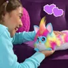 A young girl is playing with a colorful Furby toy on a purple couch. Produktbild-Vorschau