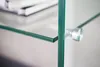 Close-up view of a modern glass shelf with silver mounting hardware. Produktbild-Vorschau