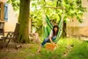 A woman is relaxing in a hammock chair in a garden, petting a cat. Náhled obrázku produktu