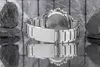 A watch is shown from the back, with its reflection on a mirrored surface. Rocks are placed on either side of the watch. Náhľad obrázku produktu