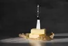A knife is stuck in two blocks of butter, which are placed on brown paper. Produktbild-Vorschau