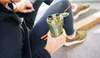 A person holding a green shaker bottle while sitting down. Voir les images du produit