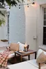 An outdoor patio scene with a small fire pit on a table, surrounded by lounge chairs and a blanket. Produktbild-Vorschau