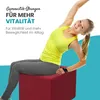 A woman is doing a fitness exercise on a red cube. Produktbild-Vorschau