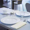 A table setting with plates, glasses, and cutlery, suggesting a dining or restaurant environment. Anteprima dell’immagine prodotto