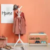 An entryway scene with a shoe rack, coat rack, and artwork. Produktbild-Vorschau