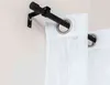 A close-up view of a black curtain rod mounted on a white wall, with white curtains hanging from it. Produktbild-Vorschau