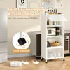 A white kitchen shelf unit with various items on its shelves, placed in a kitchen setting. A robotic vacuum cleaner is shown on the floor in front of the shelf. Produktbild-Vorschau