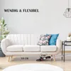 A white sofa in a living room with a vacuum cleaner underneath, demonstrating its ability to fit into tight spaces. Produktbild-Vorschau