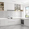 A modern, minimalist kitchen with white cabinets, marble-look backsplash, and a sleek range hood. Náhled obrázku produktu