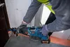 A person wearing work gloves and a high-visibility vest is using a Bosch reciprocating saw to cut through a pipe. Produktbild-Vorschau