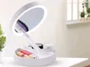 A white makeup mirror with LED lights and storage compartments for cosmetics, placed on a white surface. Náhľad obrázku produktu