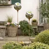 Two reflective garden spheres on stakes in a garden setting. Produktbild-Vorschau