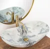 A marble sink with a gold faucet is shown in a bathroom setting, reflected in a round mirror. Anteprima dell’immagine prodotto