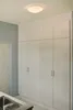 A built-in white cabinet with multiple doors and a ceiling light fixture above. Produktbild-Vorschau