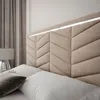 A close-up view of a bed with a padded headboard and pillows. Produktbild-Vorschau