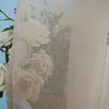 A close-up view of a sheer curtain with a floral pattern of roses. Produktbild-Vorschau