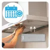 Hands installing a metal filter into a kitchen range hood, with an overlay graphic indicating a calendar and a '3x' cycle. Produktbild-Vorschau