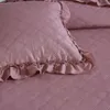 A close-up view of a quilted pink pillow and bedding. Produktbild-Vorschau