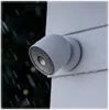 A security camera mounted on a white wall during a rain shower. Voir les images du produit