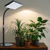 A grow light illuminates several potted houseplants on a wooden table. Produktbild-Vorschau