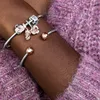 A close-up shot of a person's arm wearing a Pandora bracelet with charms, against a textured purple sweater. Anteprima dell’immagine prodotto